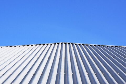 Corrugated metal roofing on a house with a blue sky behind it by Bryan Exteriors