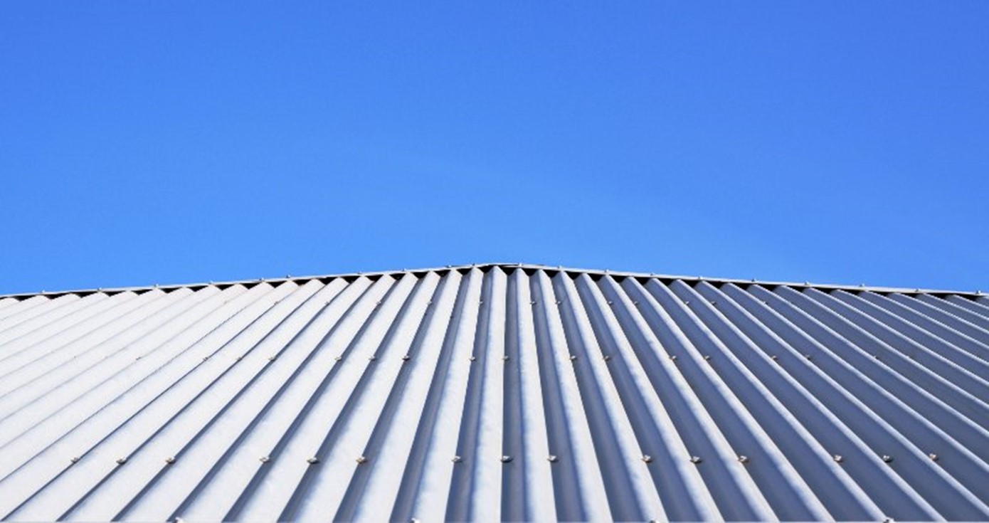 Corrugated metal roofing on a house with a blue sky behind it by Bryan Exteriors