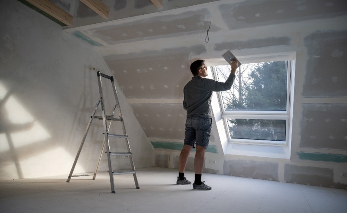 Man finishing the drywall in an attic by Bryan Exteriors